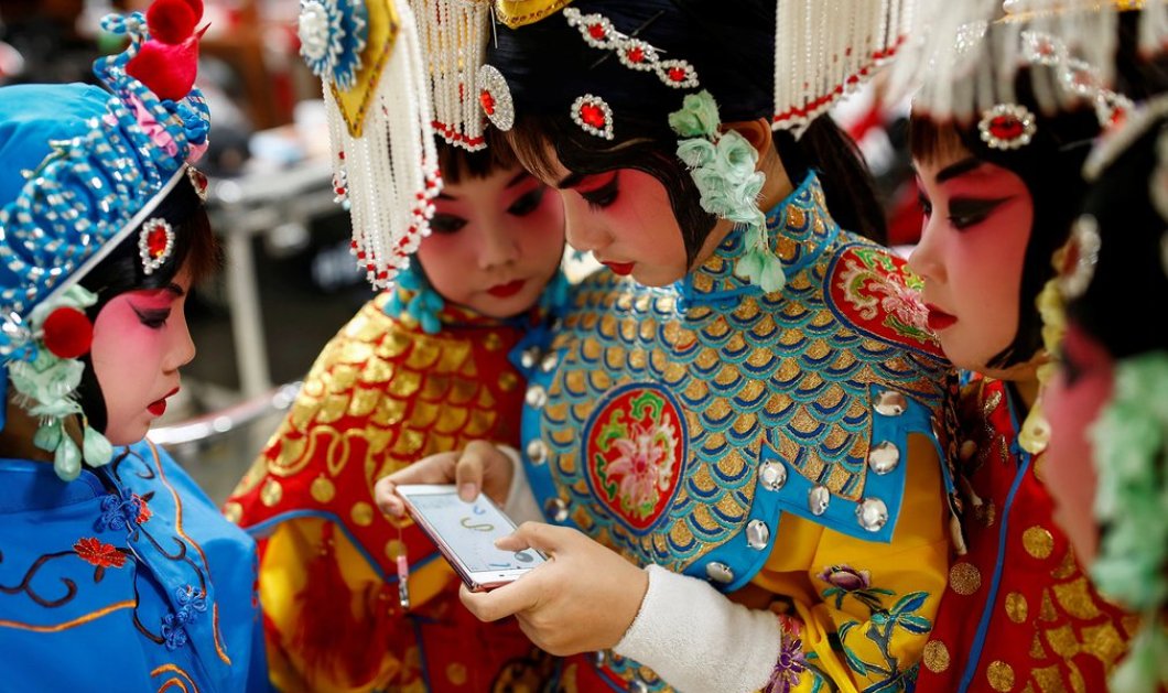 Κορίτσια παίζουν με το κινητό τους στο διάλειμμα ενός διαγωνισμού Κινέζικης Οπερας, της Εθνικής Ακαδημίας Θεάτρου στο Πεκίνο - Picture: Thomas Peter/Reuters