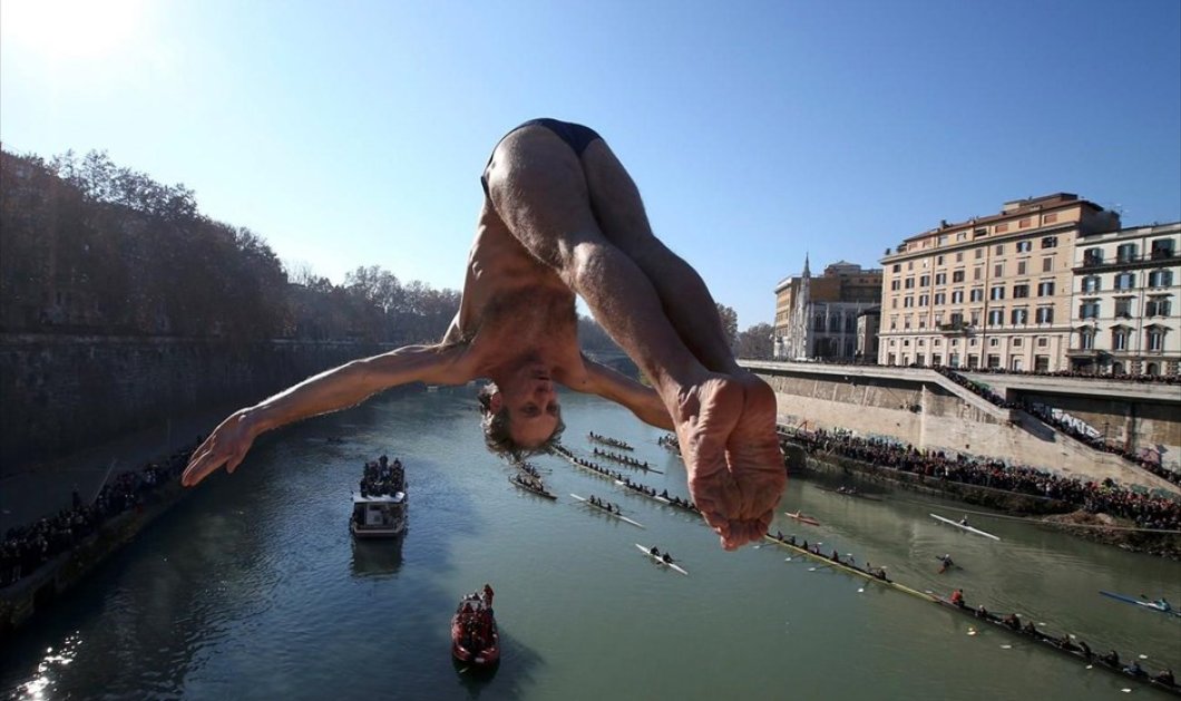 Ένας άντρας βουτά στα νερά του ποταμού Τίβερη από γέφυρα, στο πλαίσιο των εορτασμών για τη νέα χρονιά, στην Ιταλία - Picture: REUTERS / ALESSANDRO BIANCHI