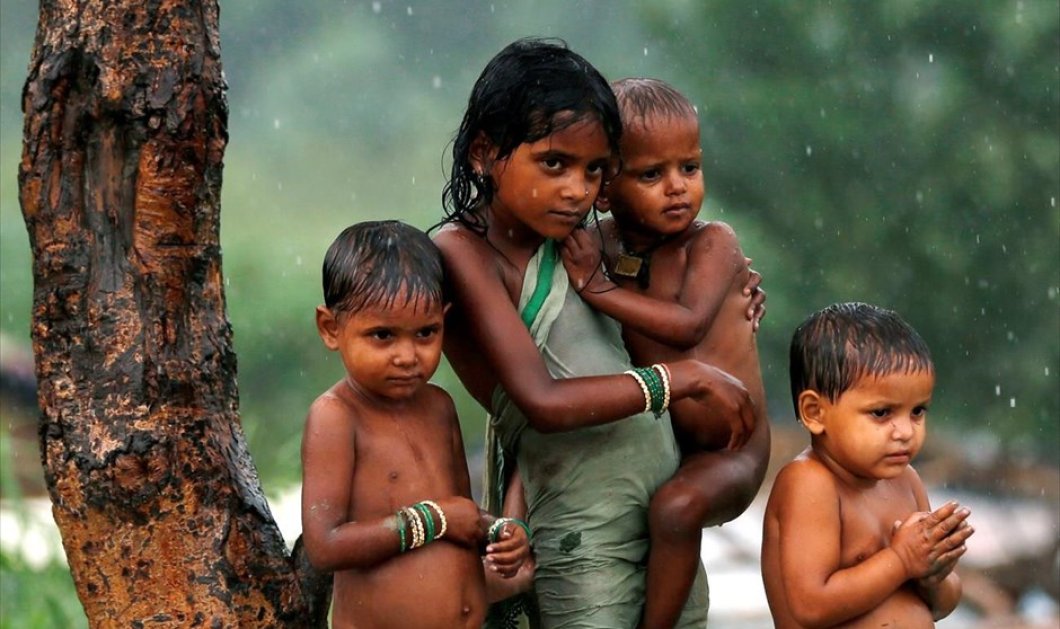 Παιδιά προφυλάσσονται από τη βροχή κάτω από δέντρο στο Νέο Δελχί - Picture: REUTERS / ADNAN ABIDI 