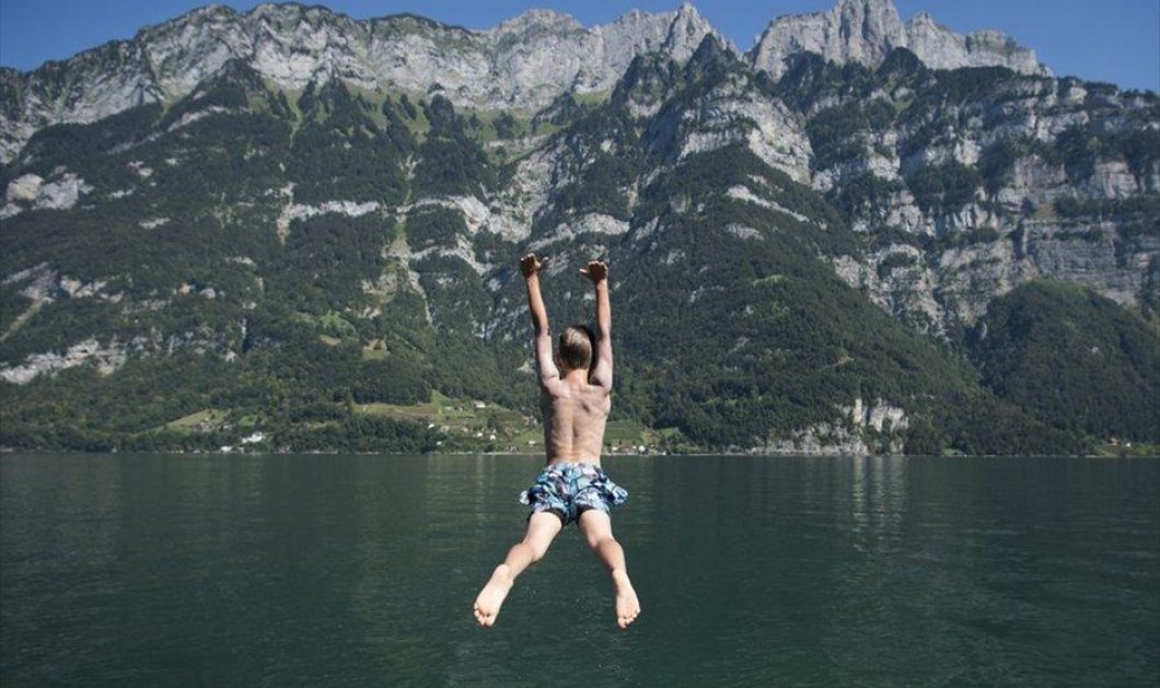 Ένα αγόρι κάνει βουτιά στη λίμνη Walensee, στην Ελβετία - EPA / GIAN EHRENZELLER
