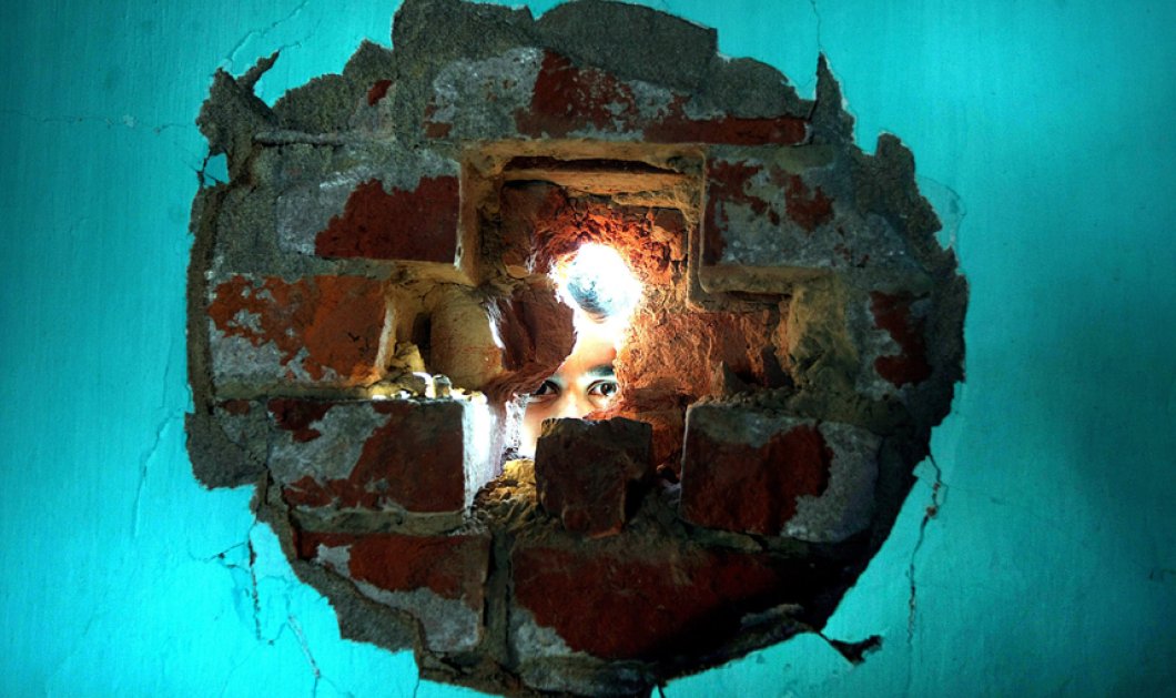 01/02/15: Ινδία: Ένα φοβισμένο αγόρι, κρυφοκοιτάζει μέσα από μια χαραμάδα στον τοίχο - Φωτό: Jaipal Singh/EPA