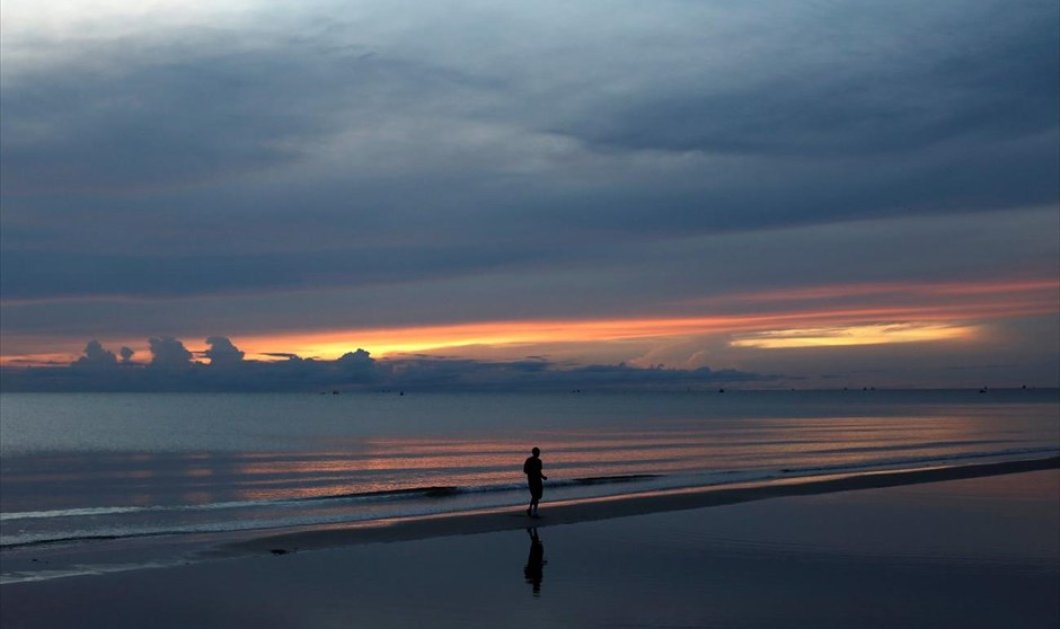 Ένας άντρας κάνει τζόκινγκ τα ξημερώματα σε μια παραλία στην περιφέρεια Χουά Χιν, στην Ταϊλάνδη - REUTERS / JORGE SILVA