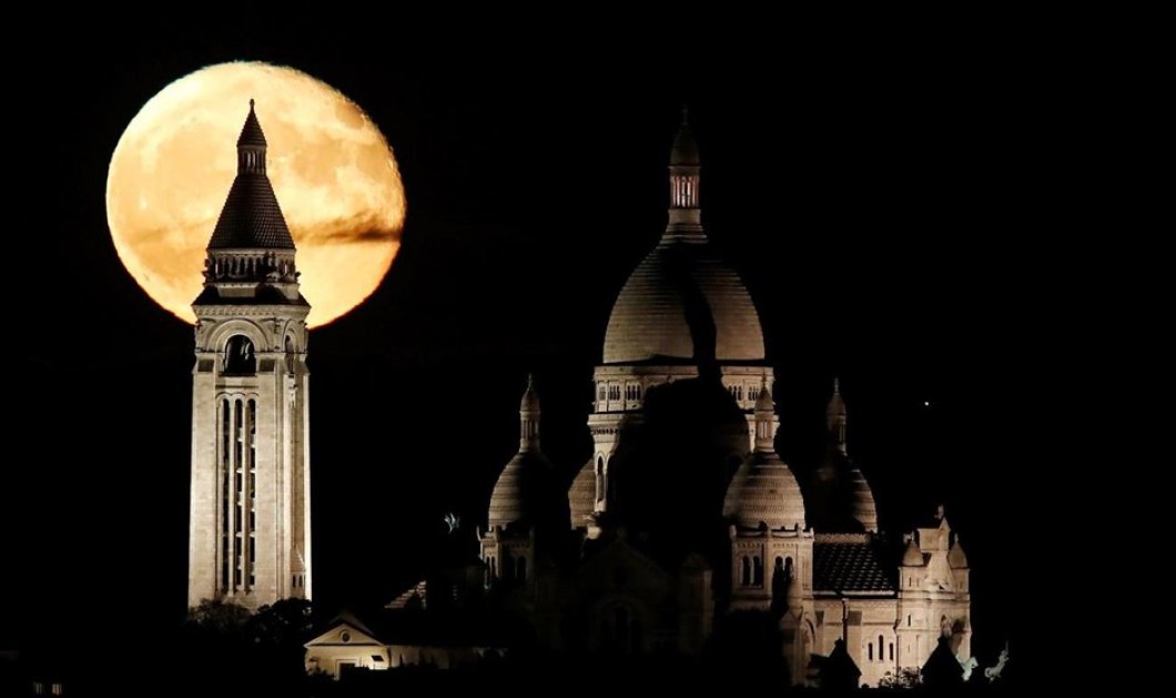 Το φεγγάρι διακρίνεται πίσω από τη Βασιλική της Ιερής Καρδιάς  Σακρέ Κερ στο Παρίσι  - Φωτογραφία: REUTERS / CHRISTIAN HARTMANN