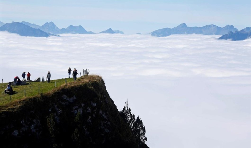 Τουρίστες απολαμβάνουν τη θέα από το όρος Niederhorn κοντά στο Ιντερλάκεν της Ελβετίας - REUTERS / RUBEN SPRICH