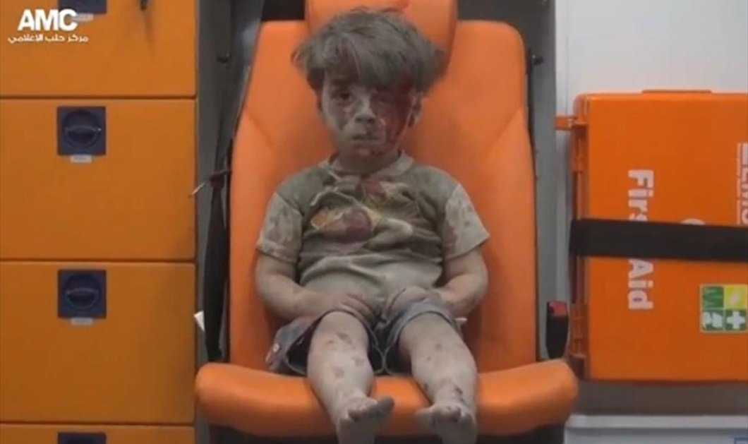 Στη φωτογραφία απεικονίζεται ένα μικρό αγόρι να κάθεται στο κάθισμα ενός ασθενοφόρου, σοκαρισμένο και καλυμμένο με σκόνη - Picture: REUTERS / REUTERS TV  